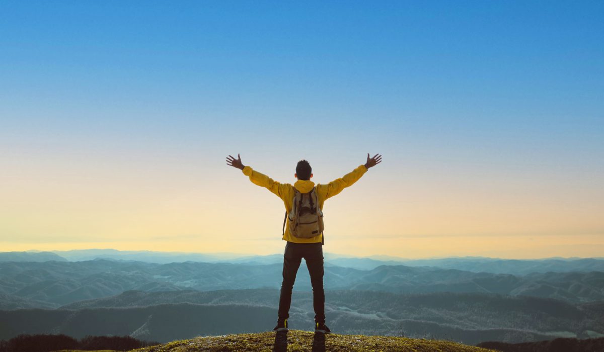 Man celebrating on top of a hill in nature