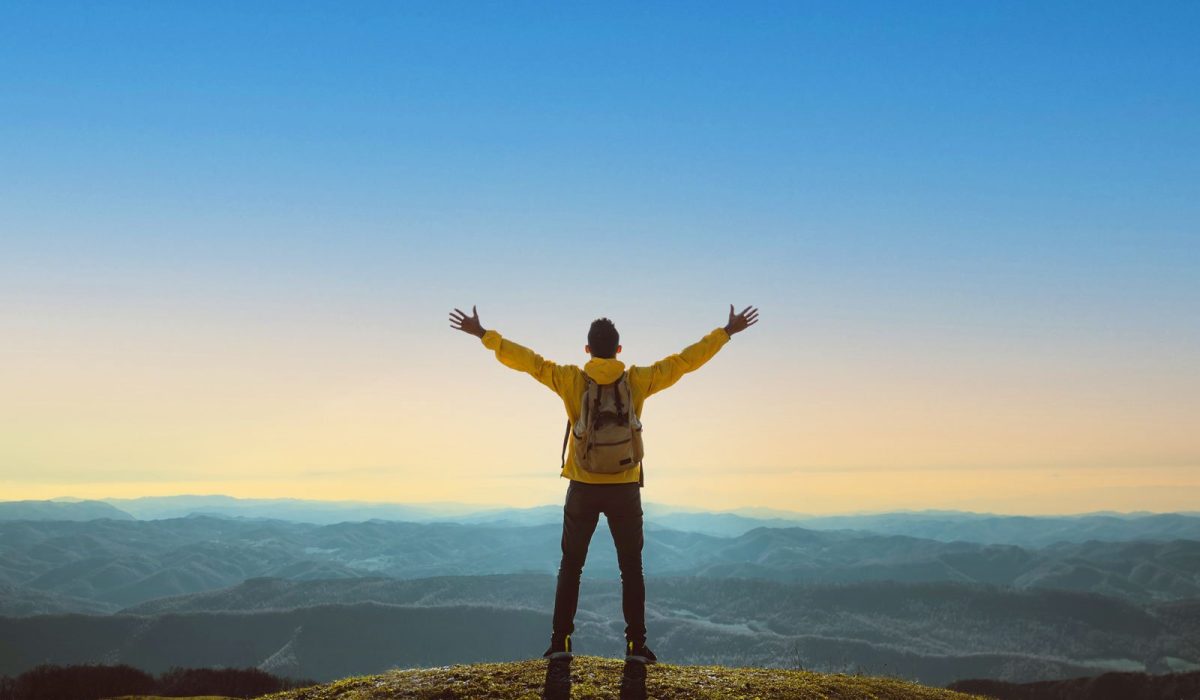 Man celebrating on top of a hill in nature